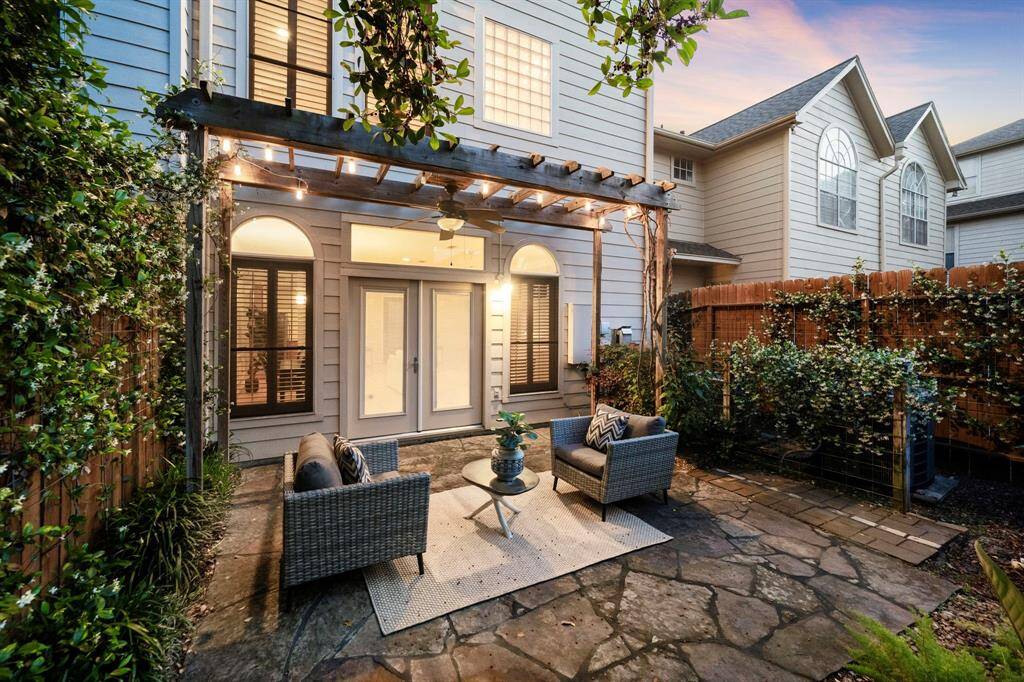 Framed by a vine-wrapped pergola, the stone patio offers a cozy outdoor setting for morning coffee or intimate evening gatherings.