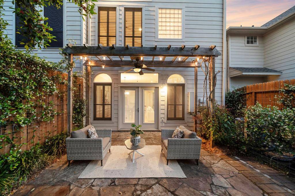 A pergola-topped patio wrapped in ivy and soft string lights creates the ultimate backyard sanctuary. Whether entertaining or unwinding, this private outdoor escape connects seamlessly to the interior through arched French doors.