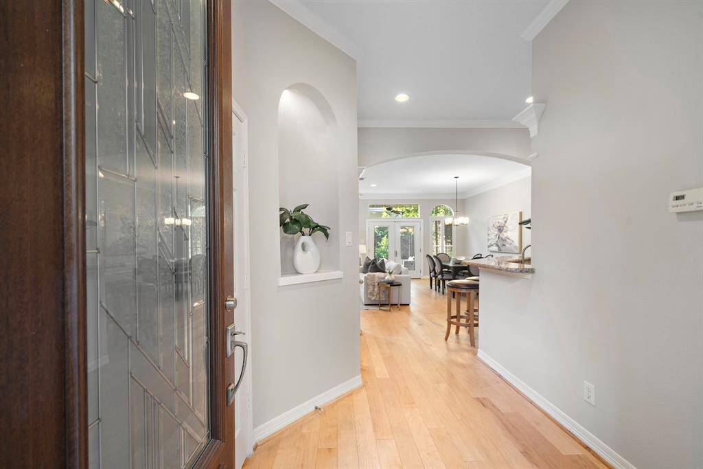 Step through the rich wood-accented front door into a welcoming foyer where arched niches and warm hardwoods lead the eye to an open, light-filled layout.