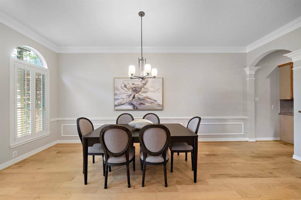 The dining area is framed by tall windows with plantation-style shutters and crisp wainscoting, offering a stylish setting for everyday meals or special occasions.