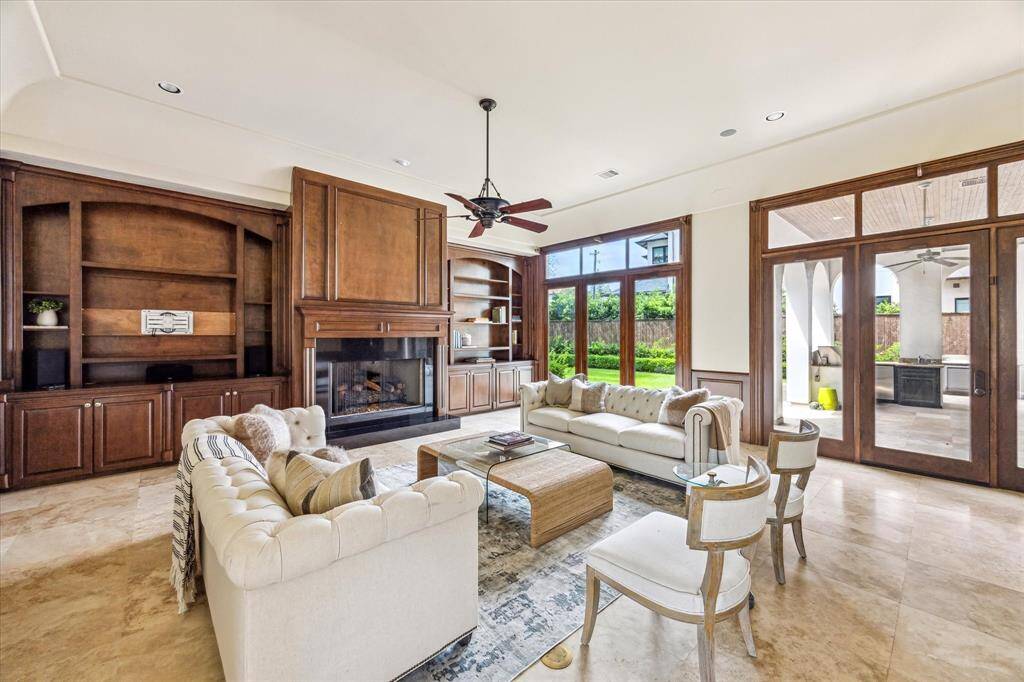 The large family room is filled with natural light from the the wall-to-wall windows and features a gas fireplace surrounded by stunning wood built-ins.