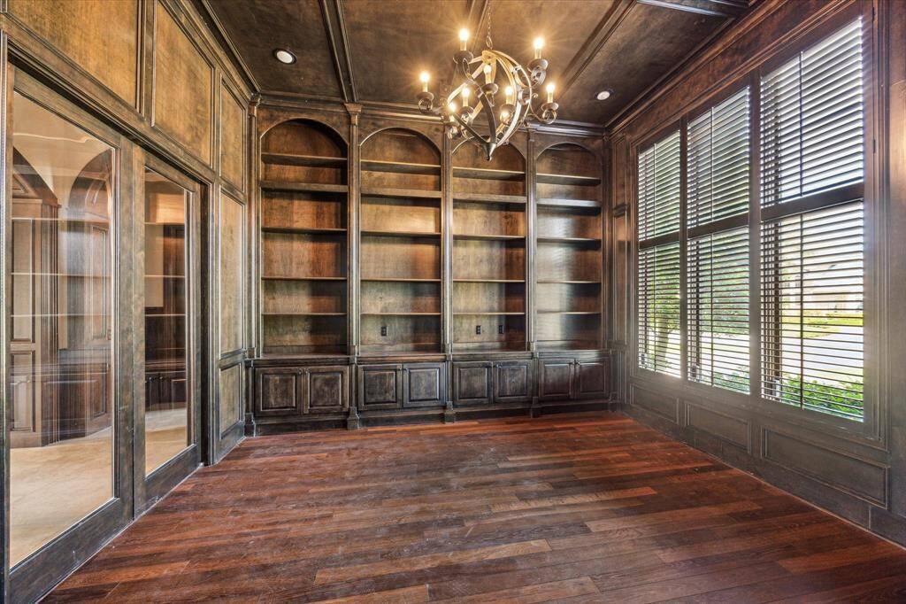 The home office features floor-to-ceiling built-ins, glass front doors and views of the front yard.