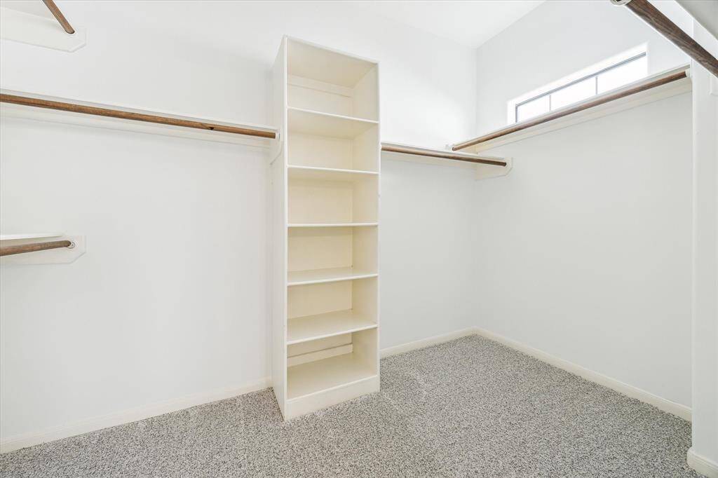 Spacious primary bedroom walk-in closet with storage.