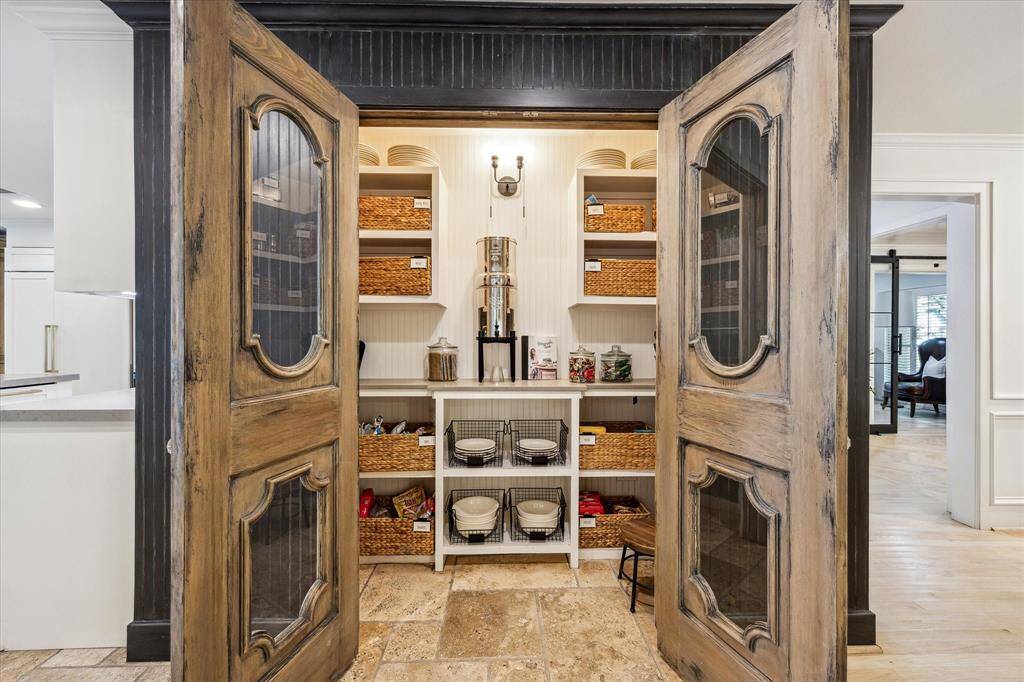 This photo showcases a stylish French pantry with rustic wooden doors that offers an exceptional storage solution.  Perfect for those seeking charm and practicality in their kitchen space.