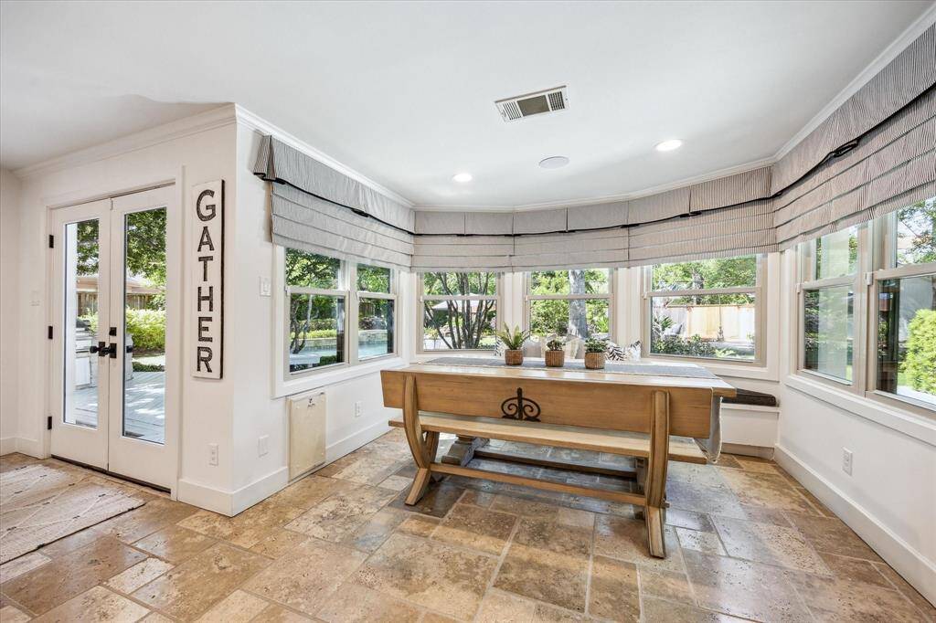 Bright breakfast area with large windows offering garden views. The space has built-in banket seating with storage and custom cusions and pillows that compliment the custom window coverings.