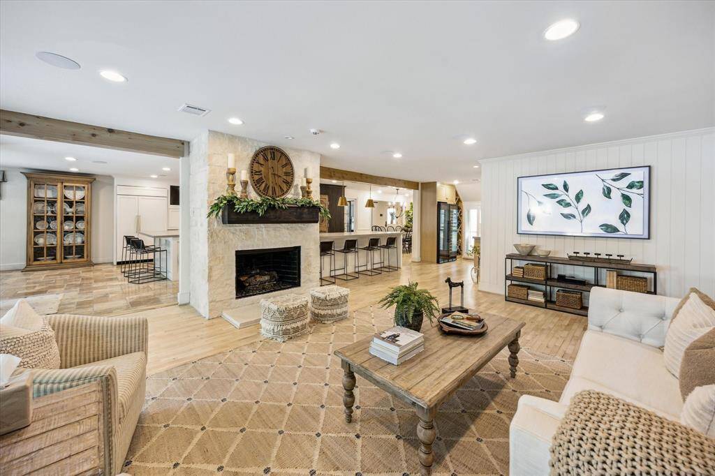 This spacious living area features an open layout with a cozy fireplace, light wood floors, and stylish decor. The room connects seamlessly to a modern kitchen with bar seating, creating a perfect space for entertaining.