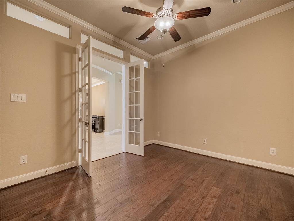 the office with double doors just past the staircase , beautiful wooden flooring and ceiling fan great space for the work from home employee