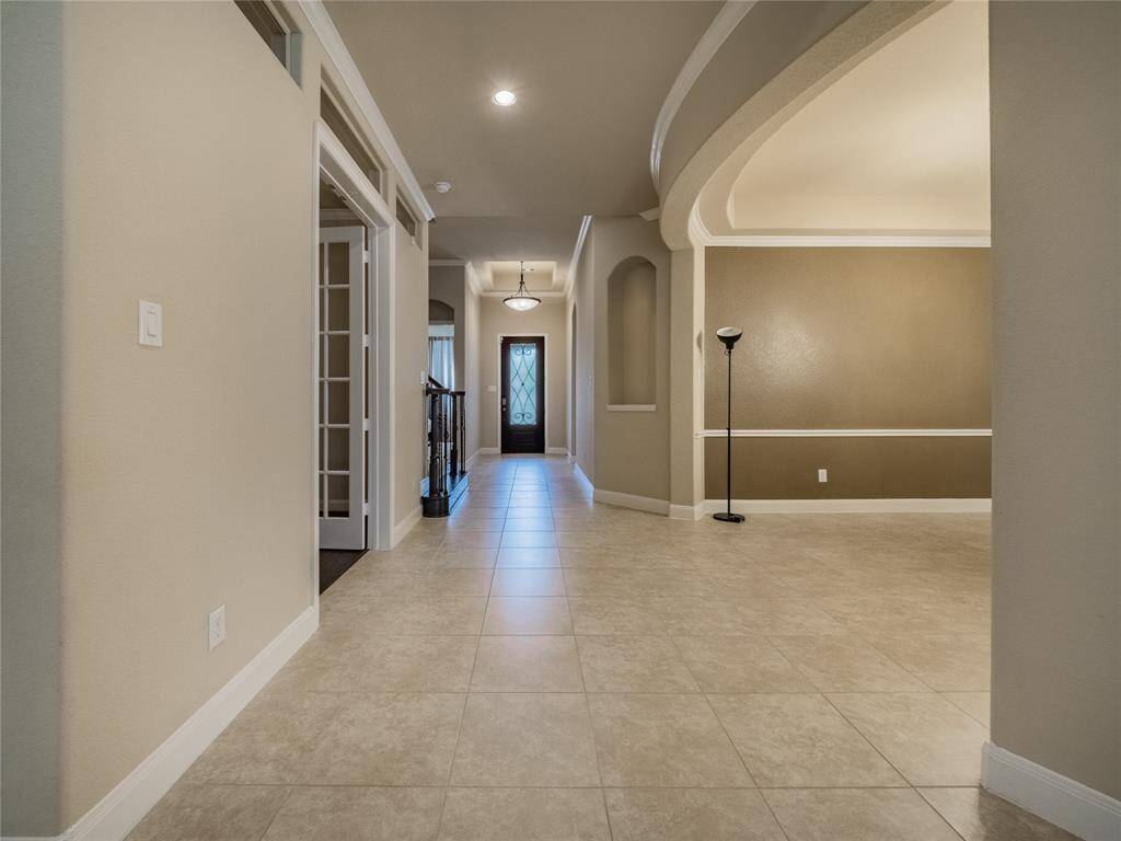 As you enter this beautiful wood and wroth iron front door you are greeted with these beautiful tile floors, tall ceilings, crown molding , wooden staircase with wroth iron spindles