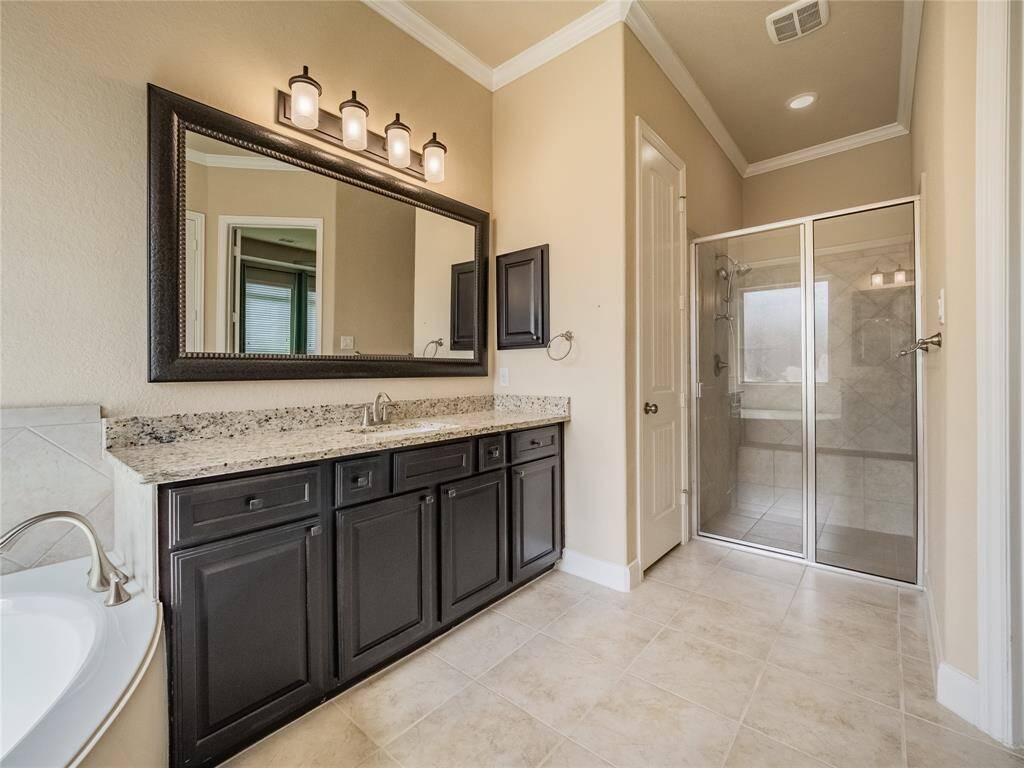 primary bathroom offers double vanities with large mirror, soaking tub and walk in glass shower