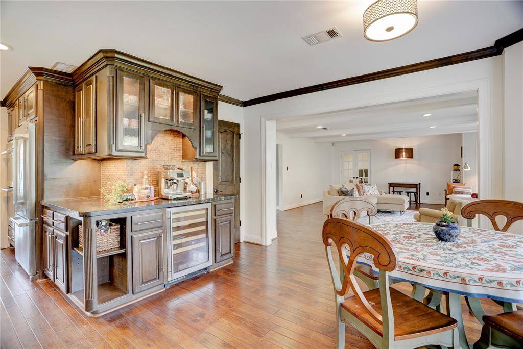 Another view showcasing the dry bar with a bevarage fridge, under-cabinet lighting, and glass-front upper cabinets.