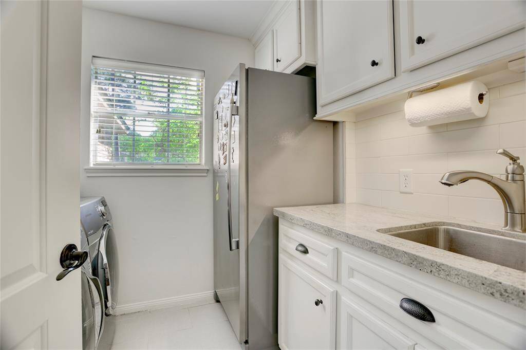 The utility room is conveniently located near the garage and backdoor. It features a sink, additional space for a full-sized fridge or freezer, plenty of cabinet storage, and a folding counter above the washer/dryer.