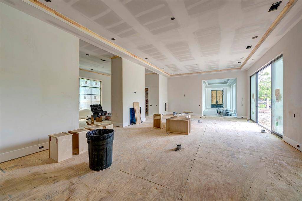 This view shows the large living room with flexible space, wine room, and wet bar on the other side of the two-sided fireplace. Great layout for entertaining! Stage of construction as of April 3, 2025.