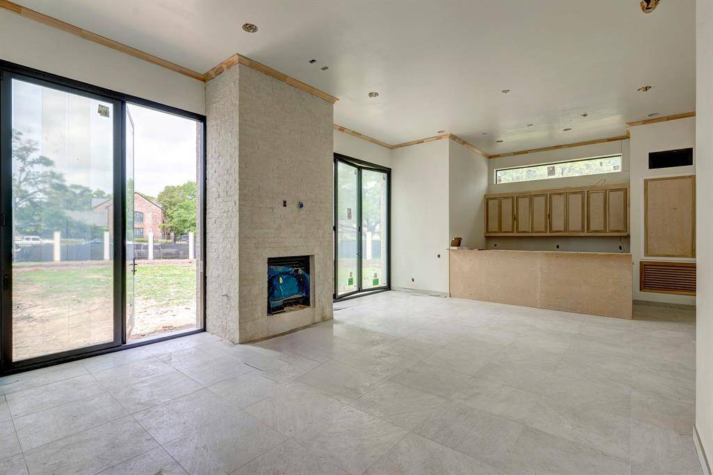 Incredible indoor/outdoor living room with fireplace and summer kitchen. Large glass doors open to the pool area. Stage of construction as of April 3, 2025.