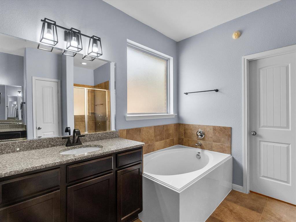 Primary en-suite bath features dual vanities, walk-in shower, soaking tub and a walk-in closet