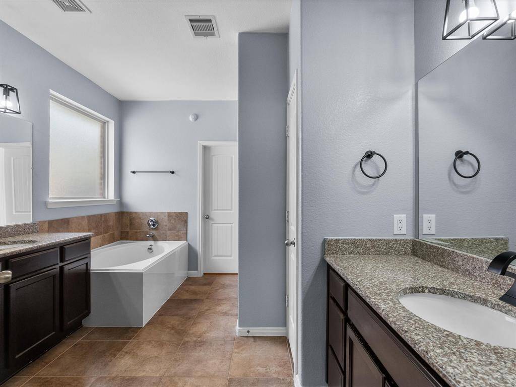 Primary en-suite bath features dual vanities, walk-in shower, soaking tub and a walk-in closet