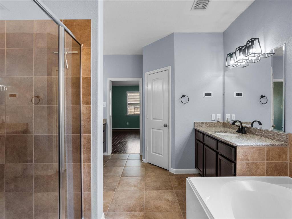 Primary en-suite bath features dual vanities, walk-in shower, soaking tub and a walk-in closet