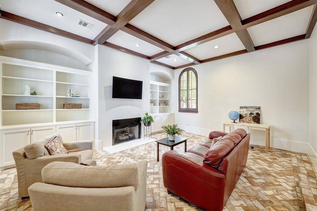 Cozy den with built-in bookshelves and exposed beams off of the study/office area