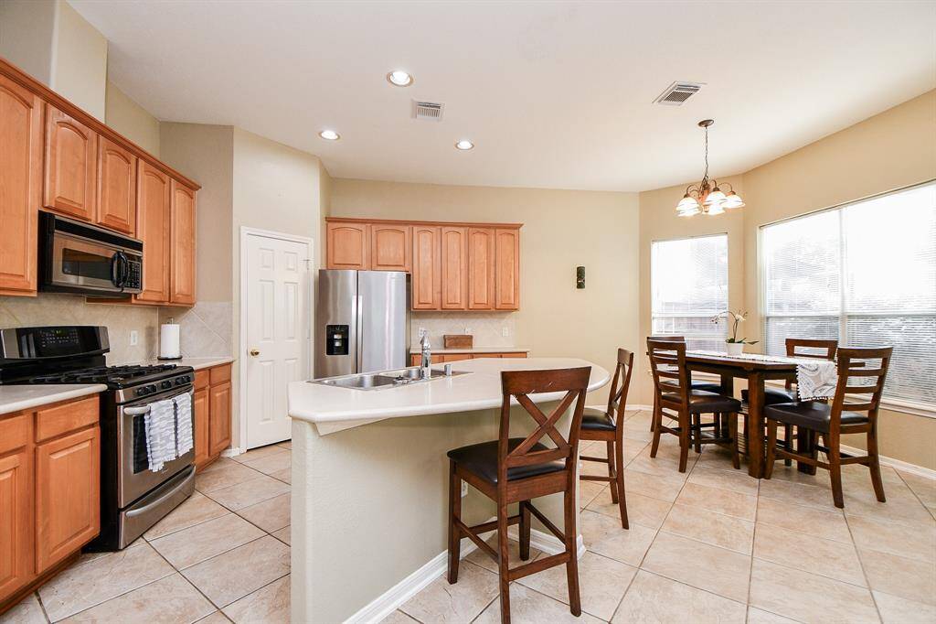 This kitchen is a cook's dream come true! Wide floor paths and walls of honey colored cabinetry span walls and floors; with the semi-circular island counter easily hosting your favorite stools.