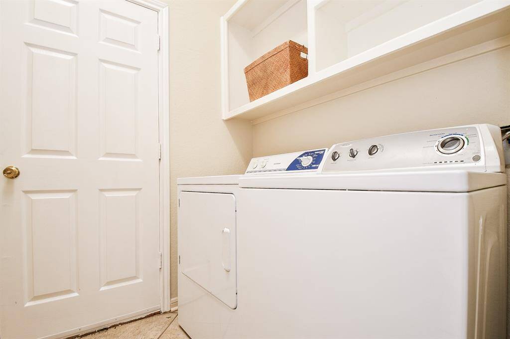 Your utility room nicely welcomes dual laundry appliances, with open storage, above.