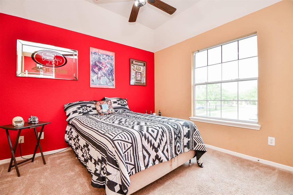 A carpeted secondary bedroom features bright natural light via this stunning window.