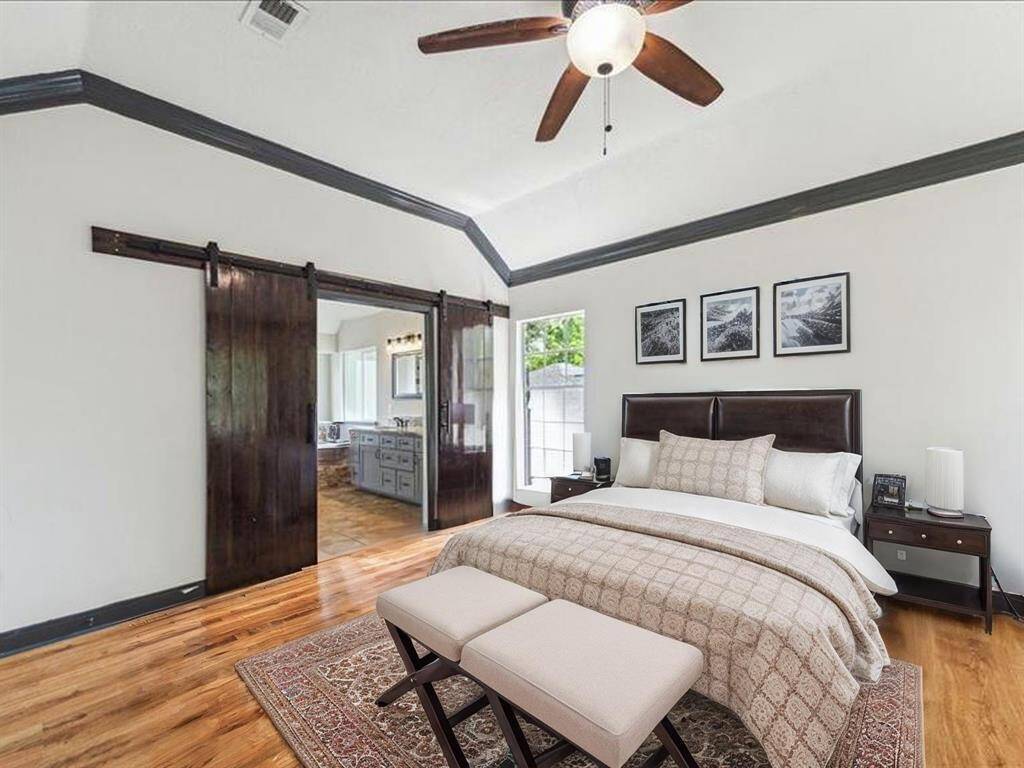 SPACIOUS PRIMARY SUITE FEATURING VAULTED CEILINGS, RICH WOOD FLOORS, AND BARN DOORS OPEN TO A FULLY REMODELED BATHROOM. **This room has been virtually staged.