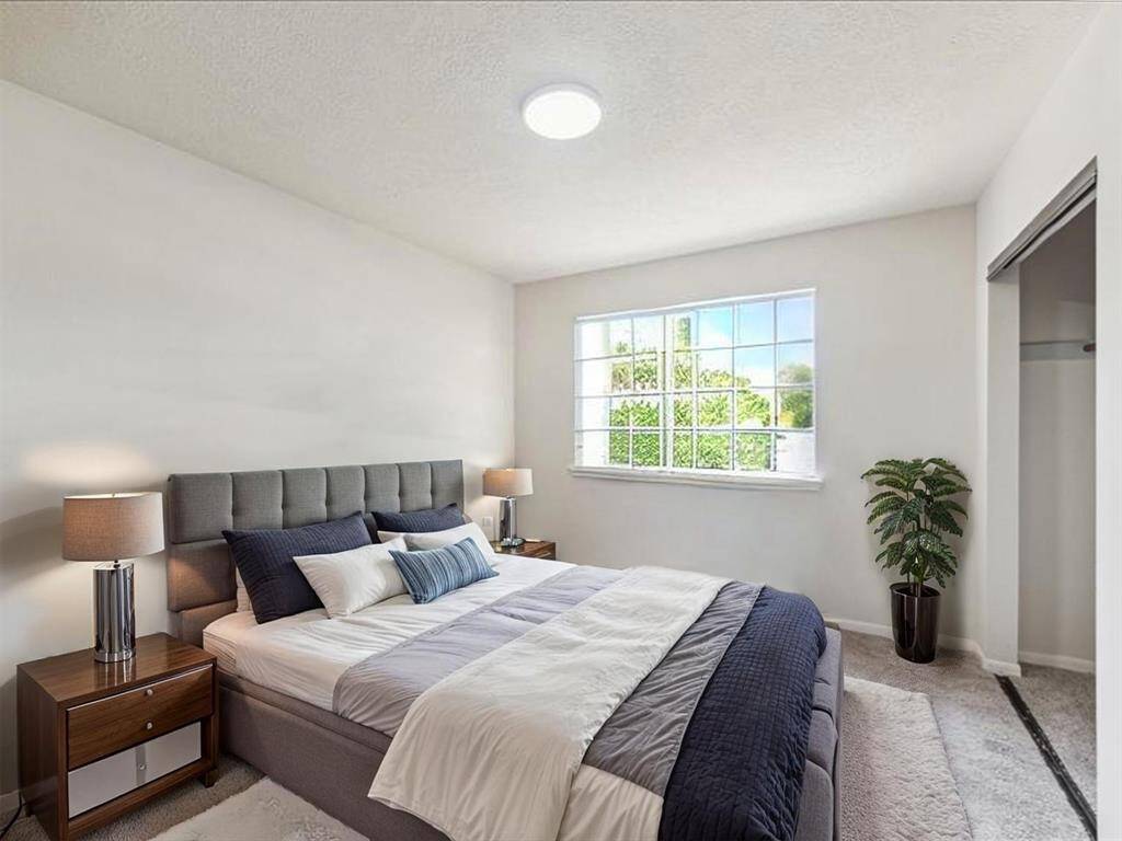 BEDROOM 4 WITH A WALL OF CLOSET SPACE, NEW CARPET FLOORING, AND A VIEW THROUGH THE OVERSIZED WINDOW—AN IDEAL RETREAT FOR REST OR STUDY. **This room has been virtually staged.