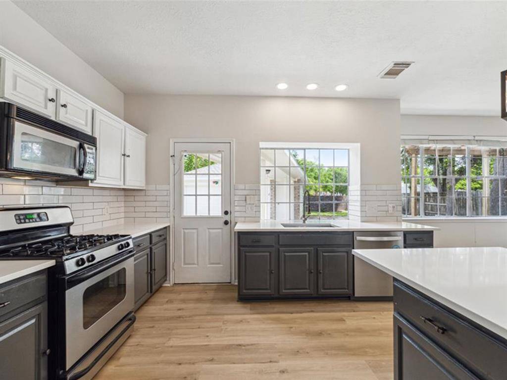 FULLY UPDATED KITCHEN FEATURING SLEEK TWO-TONE CABINETRY AND AN STAINLESS STEEL APPLIANCES.