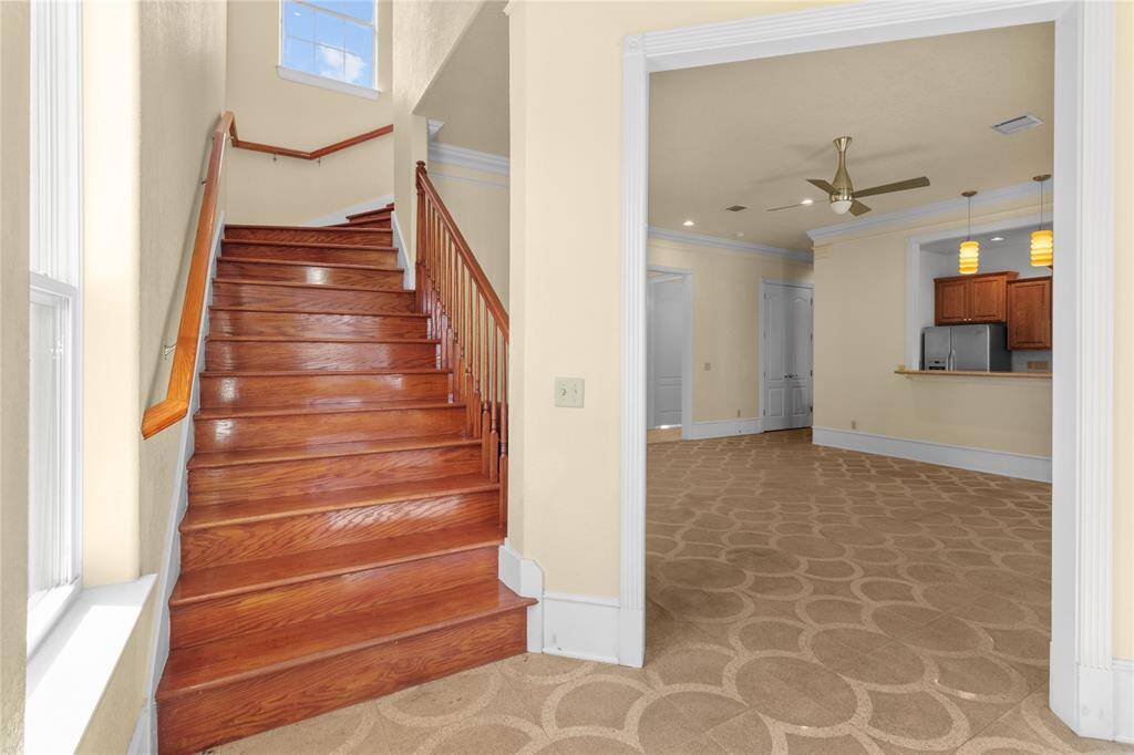 Spacious downstairs living area featuring elegant lighting, a breakfast bar, and seamless flow to outdoor views.