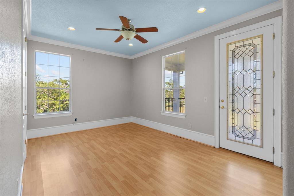 Charming upstairs bedroom featuring soft pink walls, elegant crown molding, and abundant natural light.