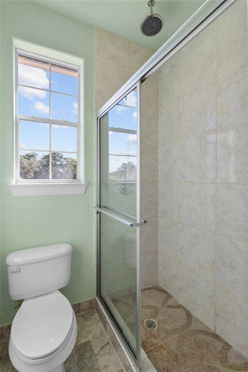 Bright and airy upstairs bathroom featuring a spacious glass-enclosed shower and a scenic window view.