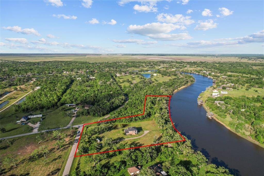 Aerial view showcasing a stunning riverside property with lush greenery and expansive views, perfect for serene living.