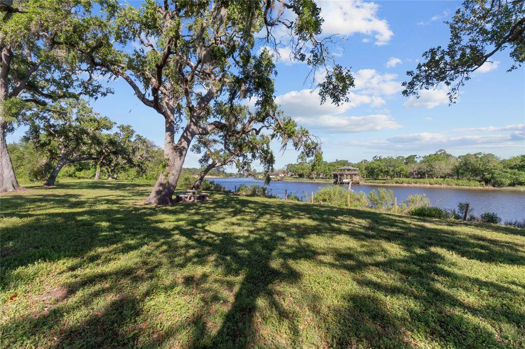 Serene riverfront view from the yard, framed by mature trees—perfect for relaxation and outdoor gatherings.