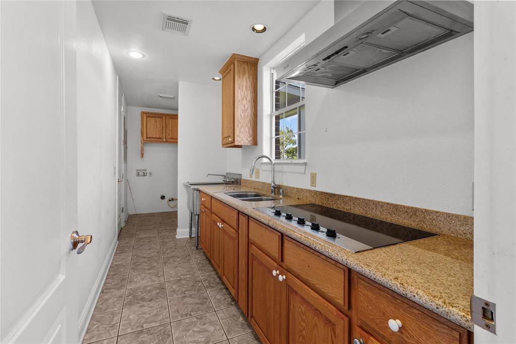 Modern kitchen with sleek countertops, ample cabinetry, and a built-in cooktop, perfect for culinary enthusiasts.