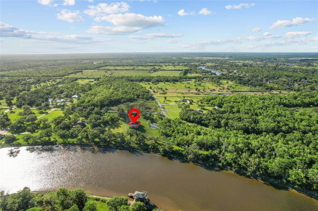 Stunning aerial view showcasing a serene riverside property surrounded by lush greenery, offering privacy and natural beauty. Perfect for those seeking tranquility and scenic landscapes.