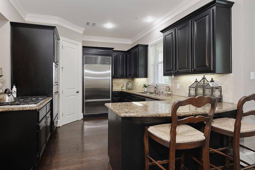 Dark cabinetry and stainless steel appliances lend to a modern touch in  this kitchen.  The breakfast bar offers perfect blend of style and functionality for home cooking and entertaining.