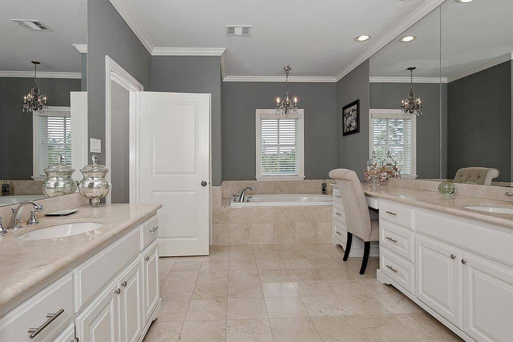 Spacious bathroom has a relaxing garden tub with chandelier and 2 individual sinks, vanity space, plenty of cabinet and counter space.