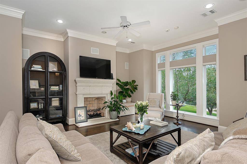 Living room features light stone fireplace and abundant natural light streaming through large windows. Perfect for relaxing or entertaining.