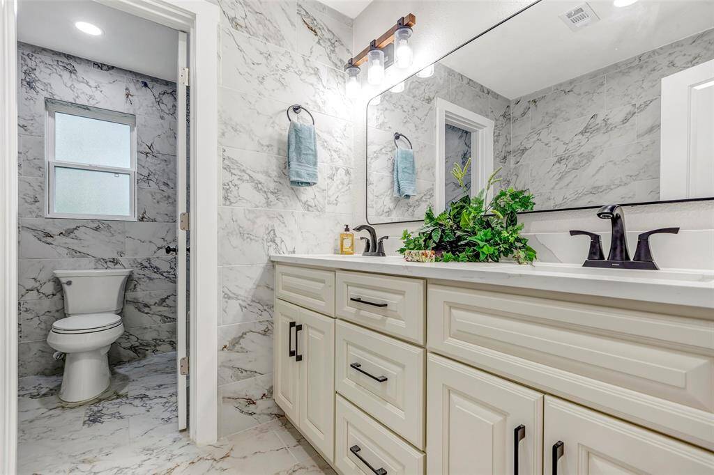 Secondary bathroom with double sink, new shower and tub, new cabinets and light fixtures.