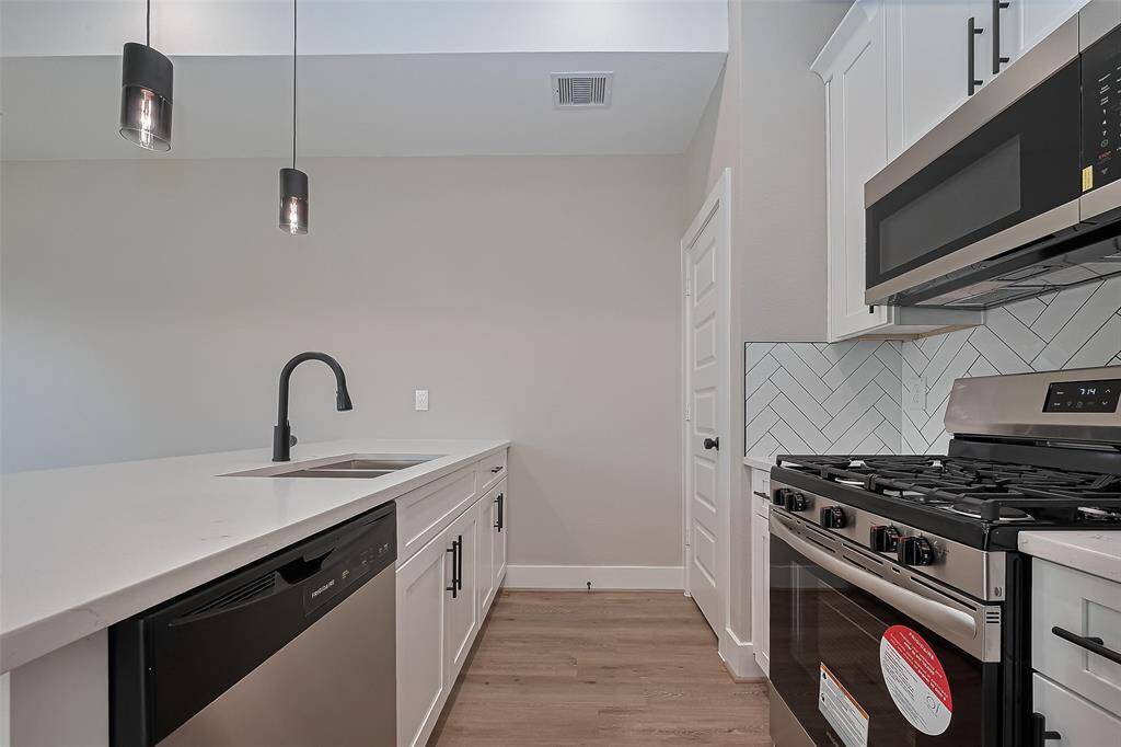 Chef-Inspired Kitchen with Modern FinishesCook in style with sleek quartz countertops, a deep under-mount sink with matte black faucet, and a full suite of stainless steel appliances—including a gas range. The white shaker cabinets offer ample storage, while the eye-catching herringbone backsplash adds a bold touch of texture and sophistication.