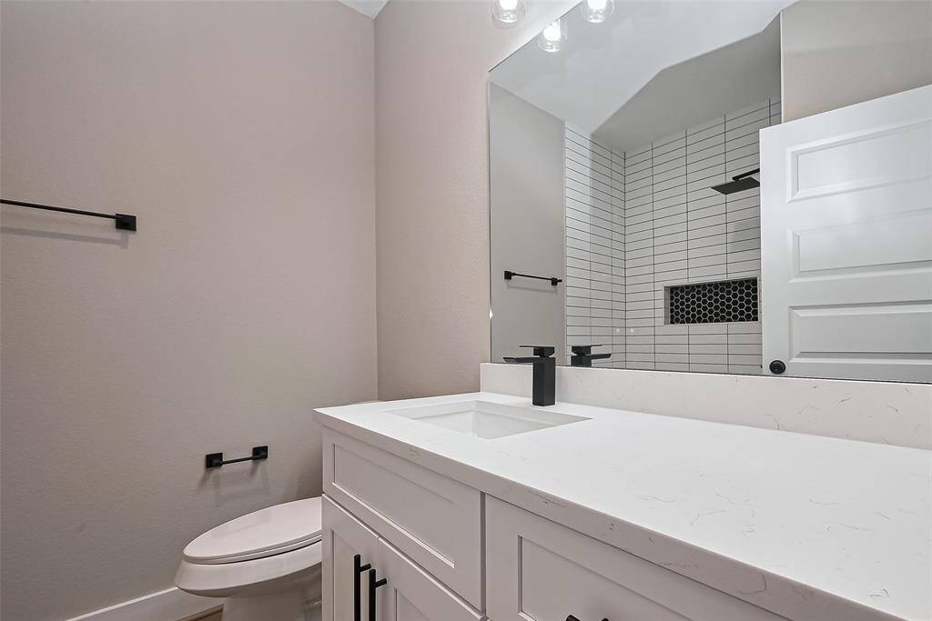 Stylish Full Bathroom with Designer TouchesEnjoy spa-like vibes in this stunning bathroom featuring a sleek quartz countertop, matte black fixtures, and a large framed mirror. The walk-in shower steals the show with vertical subway tile, built-in shelving, and a bold black hexagon accent wall—blending style and function seamlessly.