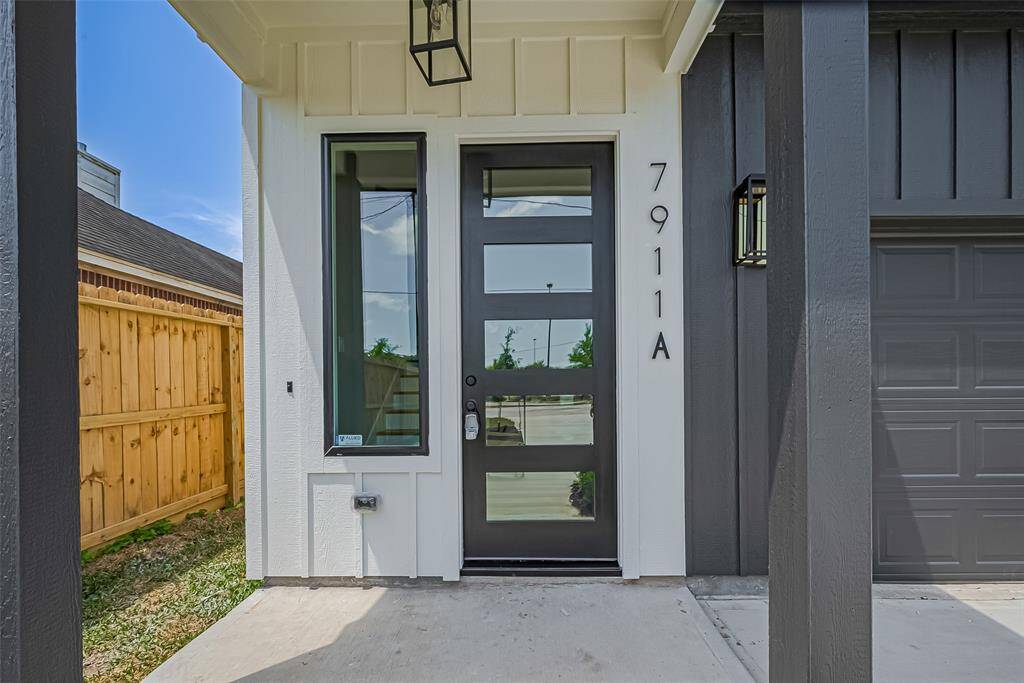 Statement Entry with Sleek Modern AppealWelcome guests through a striking glass-paneled front door framed by clean vertical siding and matte black accents. The minimalist modern vibe sets the tone for what’s inside—style, sophistication, and smart design. Natural light floods the entryway, and the covered front porch offers a warm, protected welcome.