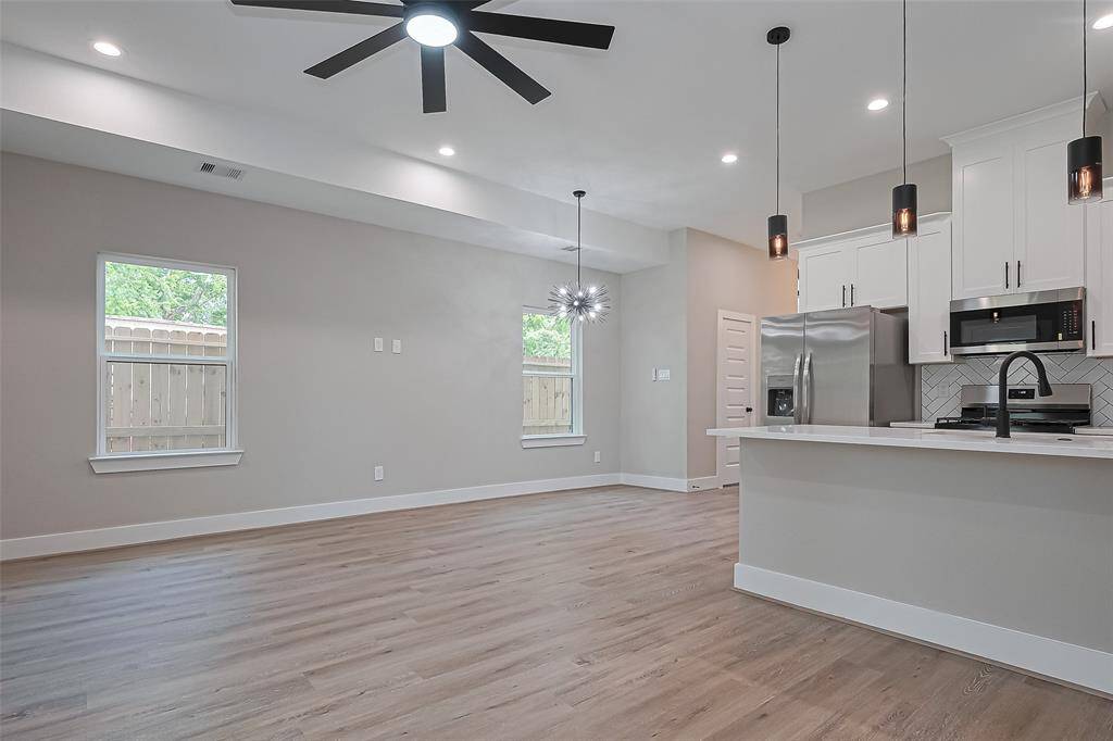 Light, Luxury, and Layout—All in OneThis angle captures the essence of modern living: warm floors, clean lines, and a kitchen that commands attention. Designer pendants, stainless steel appliances, quartz counters, and a sleek black faucet make this a chef’s dream—while the open plan ensures you're always part of the conversation.