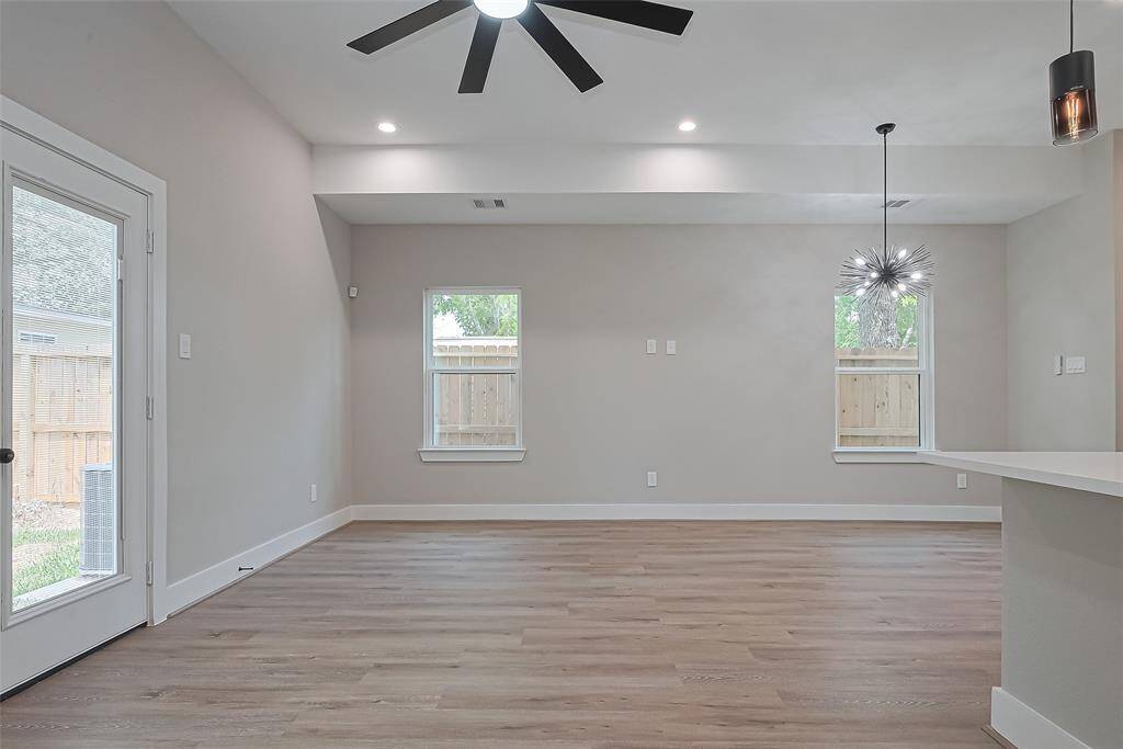 Wall-to-Wall Views and Backyard AccessFramed by large windows and a glass patio door, this living space brings the outdoors in while maintaining total privacy. Crisp walls, sleek baseboards, and a bold ceiling fan complete the modern aesthetic—perfect for customizing your dream living or entertaining zone.