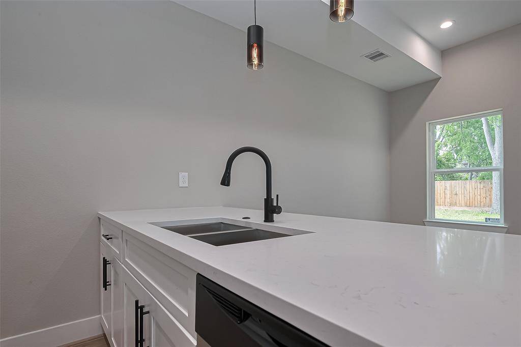 Sleek Island with Designer FinishesA true focal point, this oversized kitchen island features a deep under-mount sink, matte black pull-down faucet, and quartz countertops with subtle veining. Paired with minimalist pendant lighting and backyard views, it's a functional and stylish space for prepping, hosting, or everyday living.