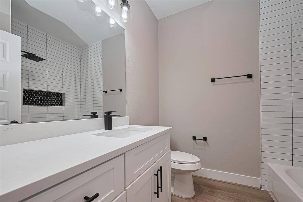 Sophisticated & Functional DesignThis full bathroom features a sleek vanity with quartz countertops, matte black fixtures, and a striking walk-in shower with vertical tile and a hexagon tile niche. Every element was chosen to elevate both style and function.