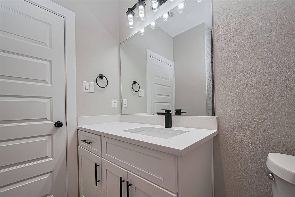 Clean Lines & Contemporary FinishesThis second upstairs bath continues the home’s elevated aesthetic with quartz countertops, bold matte black fixtures, and custom lighting that adds a touch of glam to your daily routine.