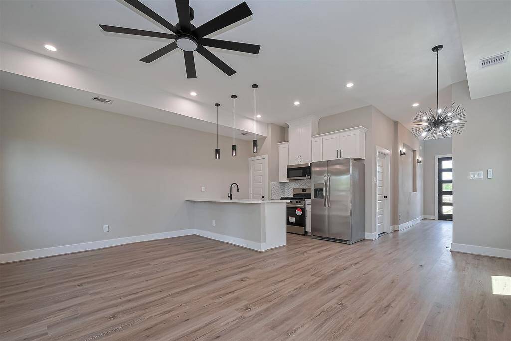 Open-Concept Layout Designed to ImpressThe heart of the home shines with high ceilings, oversized modern ceiling fans, and a seamless flow between the kitchen, dining, and living areas. The stylish kitchen boasts sleek white cabinetry, stainless steel appliances, quartz countertops, a striking black faucet, and designer pendant lights. A dramatic starburst chandelier anchors the dining space, adding flair to every meal and gathering.