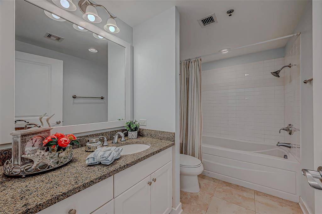 Luxurious master bathroom featuring a shower/tub combo and elegant vanity with ample storage.