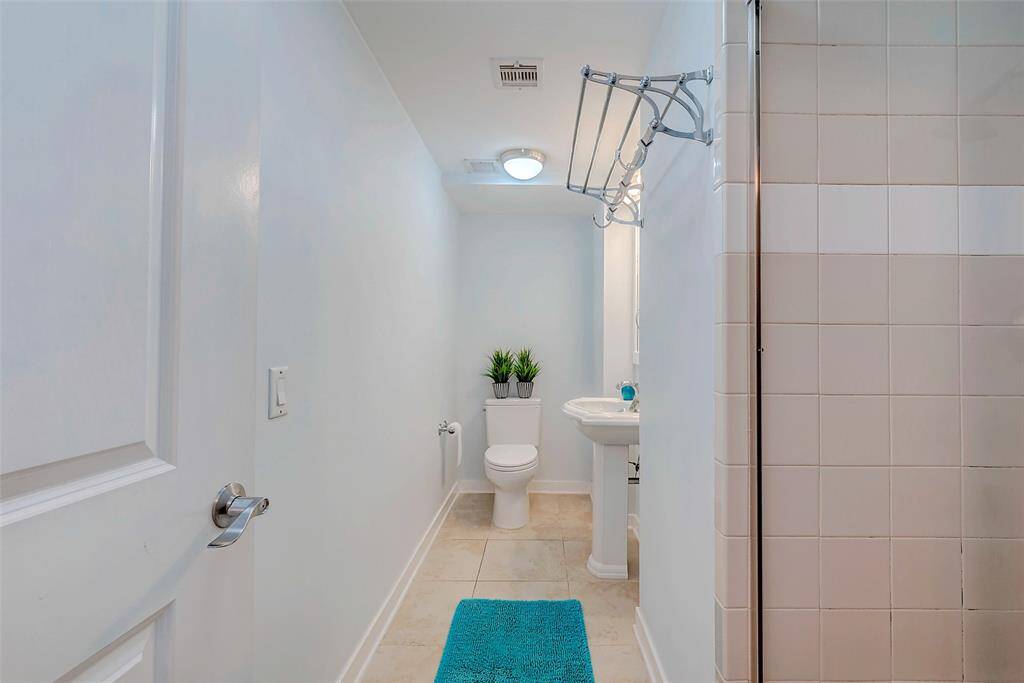 Elegant secondary bathroom featuring tile floors, a full shower, and a stylish pedestal sink.
