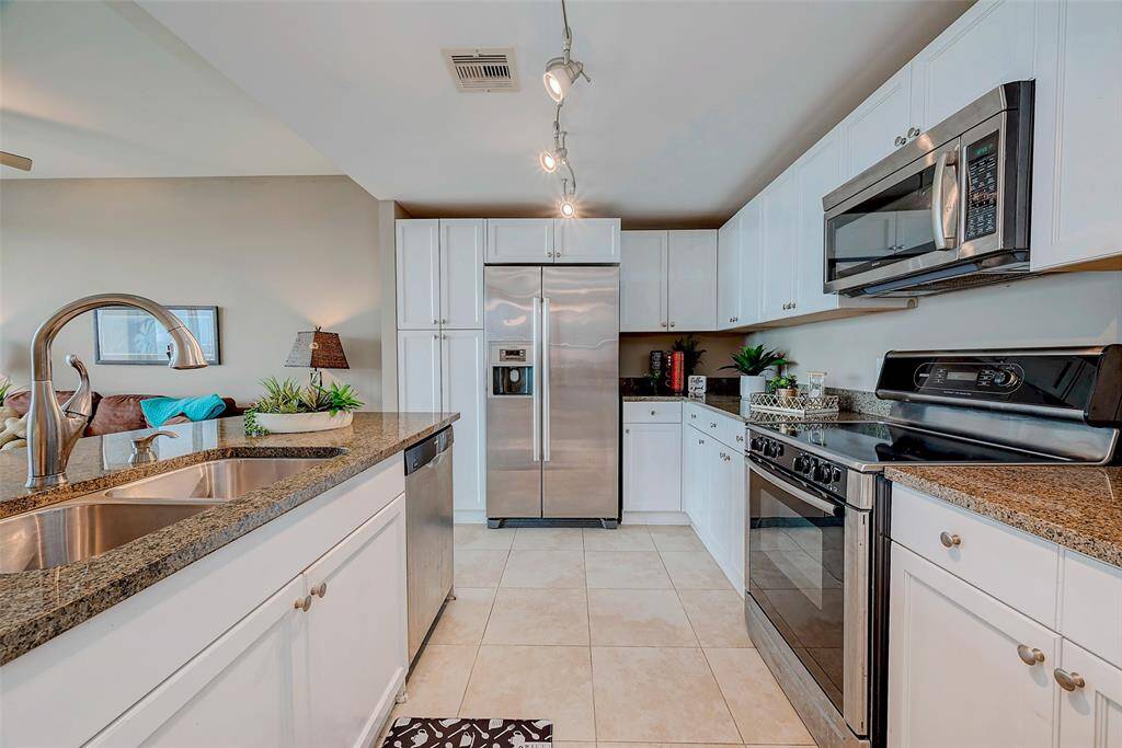 Modern kitchen with sleek granite countertops, stainless-steel appliances, and easy-care tile flooring.